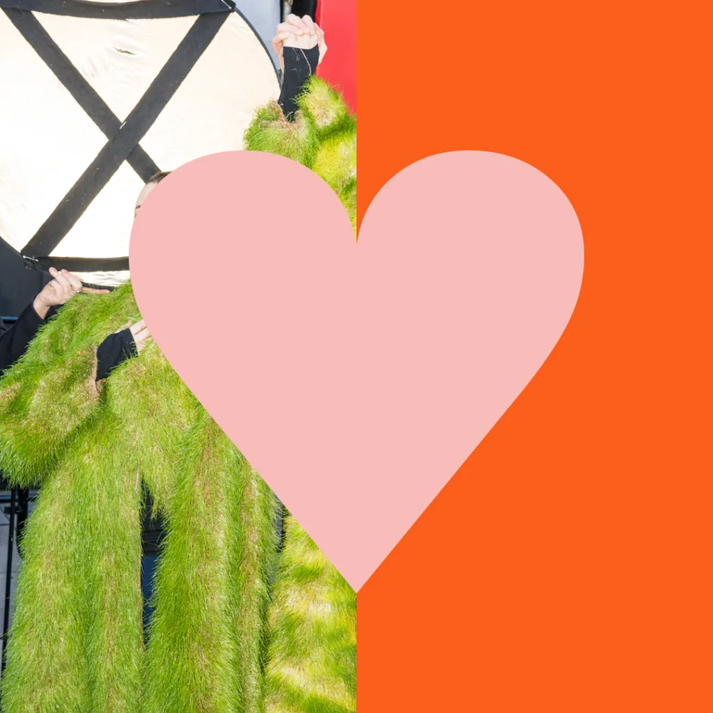Abstract artistic collage with juxtaposed imagery: one side features a person in a costume with shaggy green fur, while the other half is an eye-catching orange background with a large pink heart overlay, creating a visually striking contrast.