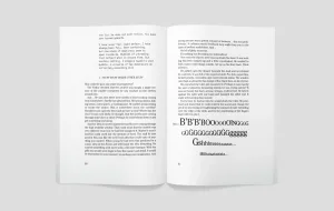 An open book with two pages visible: the left page contains structured text with paragraphs, and the right page shows large, bold lettering of the letters "b" and "g" in various sizes along with the word "ghhhhhhhh" in a large, expressive font, suggesting a creative or artistic element within the book's content.